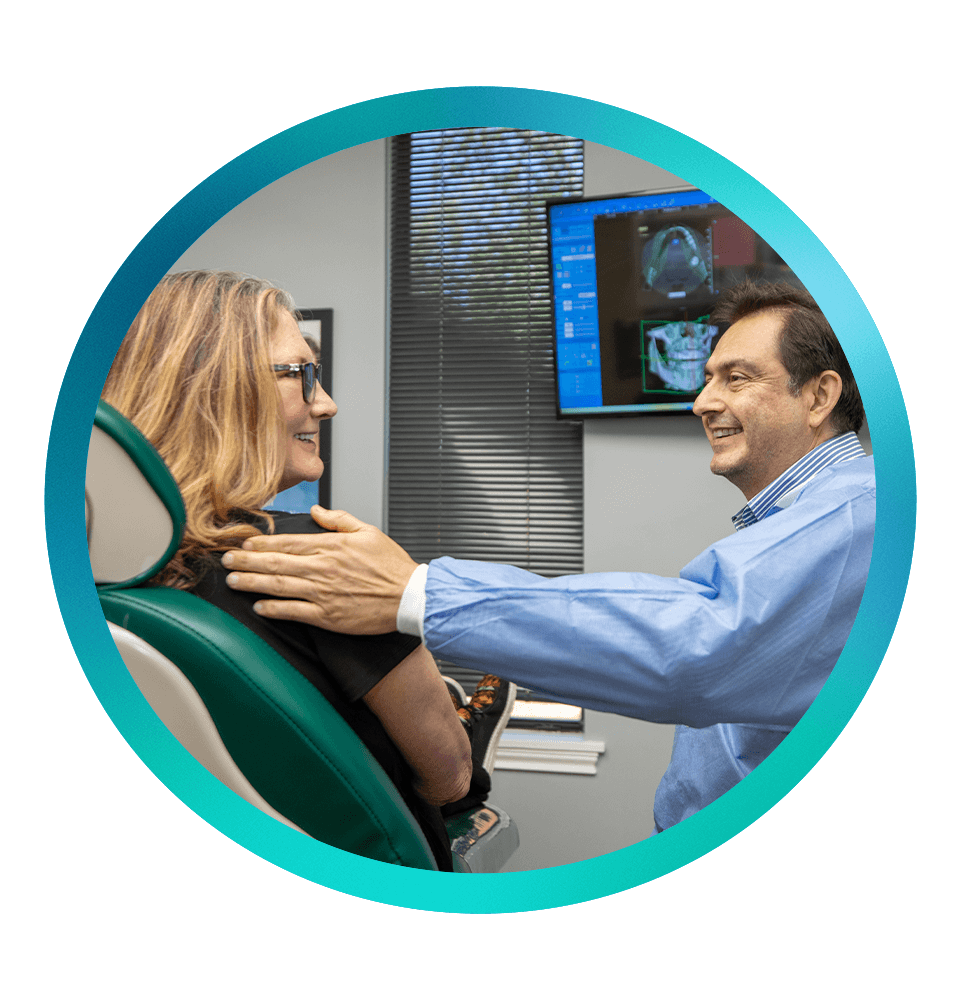 doctor and oatient smiling brightly while going over denta; treatment information